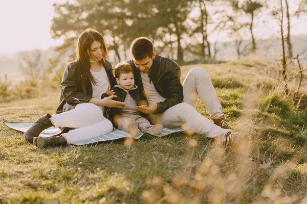 Família elegante sentado em um campo de primavera — Fotografia de Stock