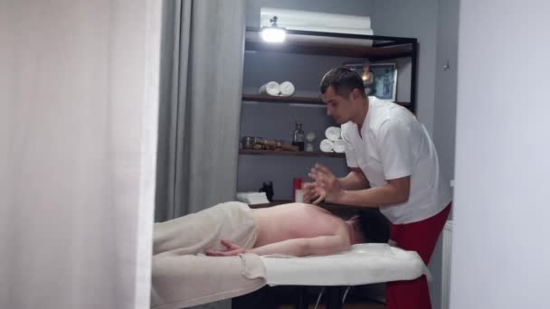Массажист в форме массажера шеи в массажной комнате — стоковое видео