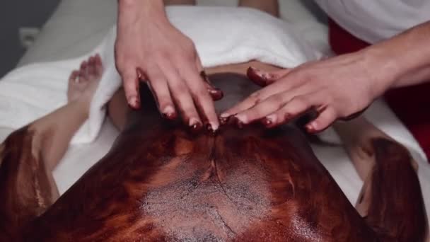 Closeup van masseur doen massage met chocolade scrub — Stockvideo