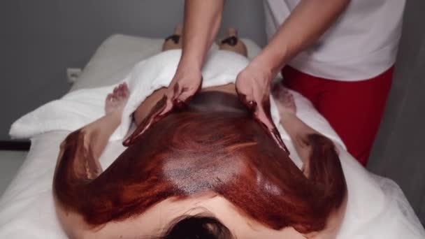Closeup van masseur doen massage met chocolade scrub — Stockvideo