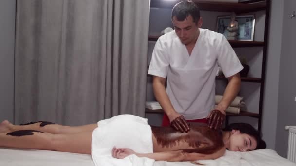 Masajista en uniforme masajea a los clientes de vuelta con máscara — Vídeos de Stock