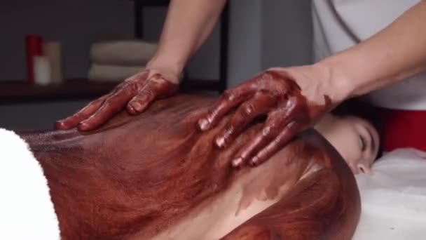 Closeup of masseur doing massage with chocolate scrub — Stock Video