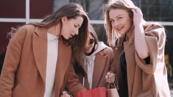 Las chicas bonitas están revisando bolsas de compras con ropa — Vídeo de stock