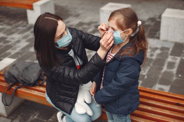 Tek kullanımlık maskeli bir kadın çocuğuna solunum cihazı takmayı öğretiyor.