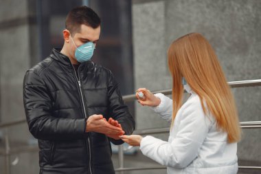 Koruyucu maskeler takan gençler el dezenfektanı sıkıyorlar.