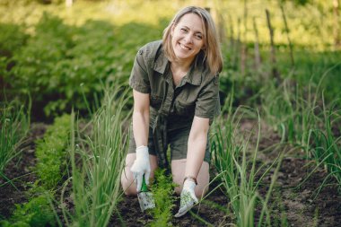 Güzel bir kadın evin yakınındaki bir bahçede çalışıyor.