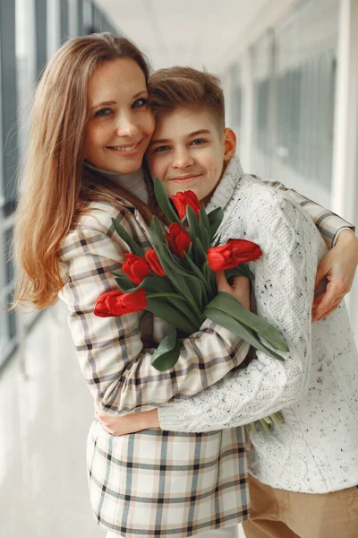 Сын дарит матери кучу красных тюльпанов в amodern Hall Стоковое Изображение