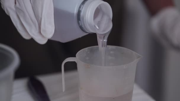 Osoba v bílých rukavicích nalévání tekutiny v misce ve studiu — Stock video