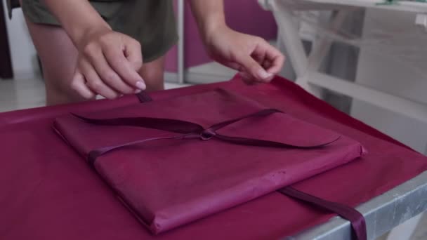 Closeup de mãos femininas embrulhando presente com papel rosa — Vídeo de Stock