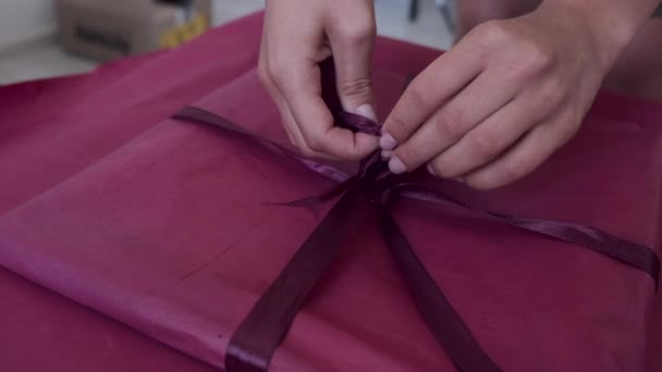 Close-up van vrouwelijke handen inpakken geschenk met roze papier — Stockvideo