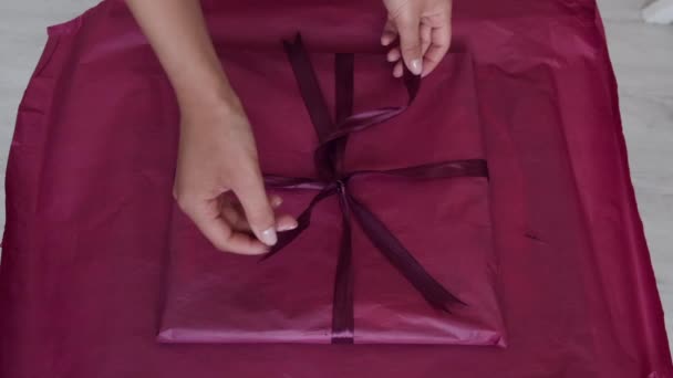 Großaufnahme weiblicher Hände, die Geschenk mit rosa Papier einwickeln — Stockvideo