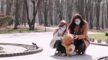 Avrupalı anne ve kızı bahar parkında karantina sırasında bir köpekle yürüyorlar.