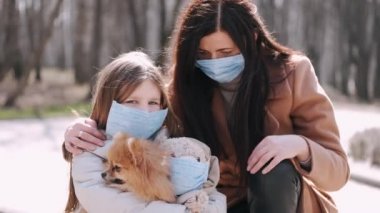 Avrupalı anne ve kızı bahar parkında karantina sırasında bir köpekle yürüyorlar.