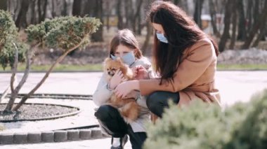 Avrupalı anne ve kızı bahar parkında karantina sırasında bir köpekle yürüyorlar.