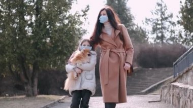 Avrupalı anne ve maskeli kızı bir köpekle parktalar.