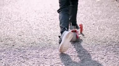 Çocuk park yolunda scooter kullanıyor.