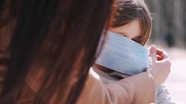 ヨーロッパの母親は使い捨てマスクの娘の顔を入れている — ストック動画