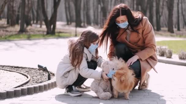 Avrupalı anne ve kızı bahar parkında karantina sırasında bir köpekle yürüyorlar. — Stok video