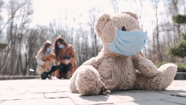 La vista de un juguete en una máscara y la madre y la hija en máscaras están en un parque — Vídeo de stock