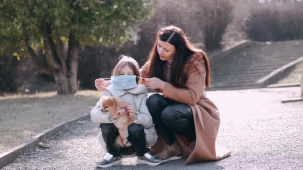 Europejska matka i jej córka w maskach są w parku z psem — Wideo stockowe