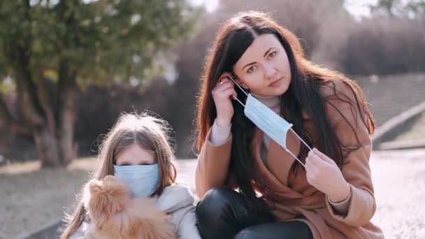 Europese moeder en haar dochter in maskers zijn in een park met een hond — Stockvideo