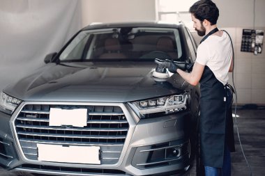 Adam garajda araba cilalıyor.