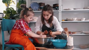 Seramik sanatçısı çocuğa seramik yapmayı öğretiyor.