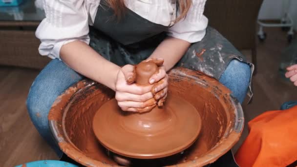 Mãos de mulher trabalhando na roda de cerâmica e fazendo pote — Vídeo de Stock