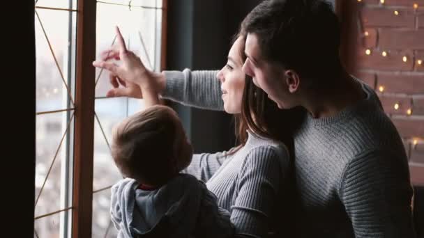 Сім'я з маленькою дитиною дивиться на вікно і вказує пальці — стокове відео
