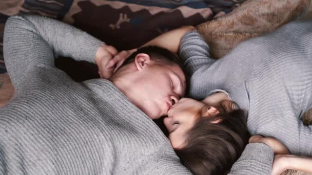 Пара в серебряных свитерах, лежащих на полу и целующихся дома — стоковое видео