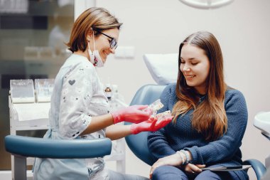 Güzel kız dişçi ofisinde oturuyor.