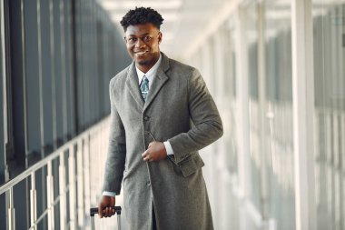 Havaalanında bavullu şık bir siyah adam var.