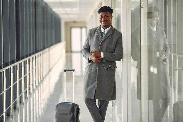 Eleganter schwarzer Mann mit Koffer am Flughafen — Stockfoto