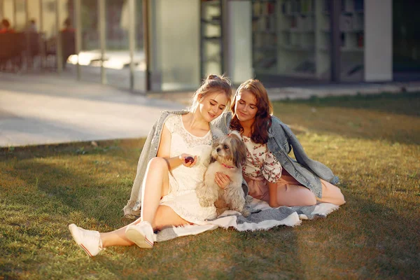 Twee meisjes zittend in een park met een hondje — Stockfoto