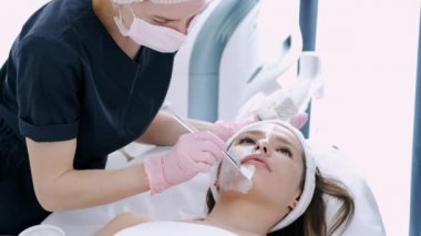 Kozmetik uzmanı kızların yüzüne güzellik salonunda krem sürüyor.