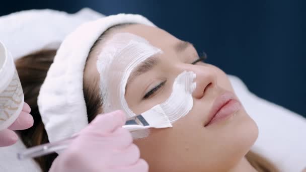 Oříznutý pohled na kosmetička dávat obličejovou masku na obličej — Stock video