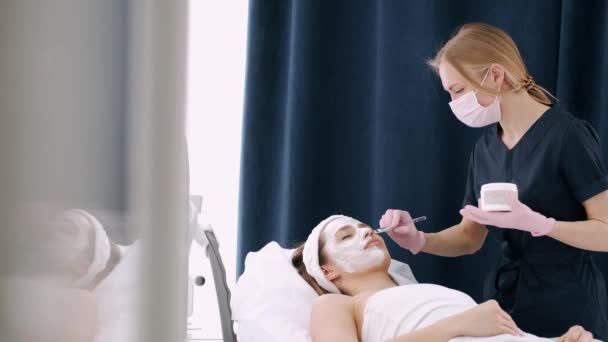 Cosmetologue frottis filles visage avec de la crème dans le salon de beauté — Video