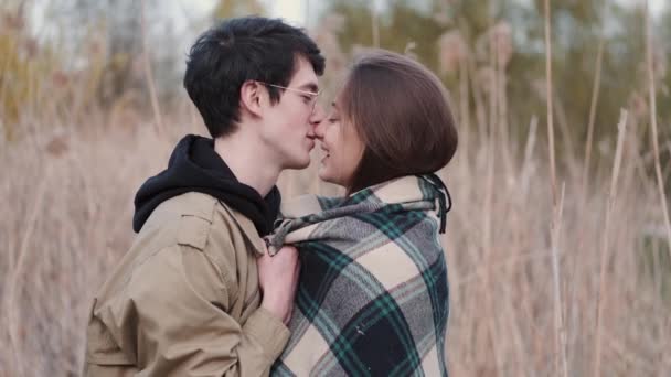 안경을 쓴 남자와 여자가 키스하고 갈대로 데이트하는 모습 — 비디오