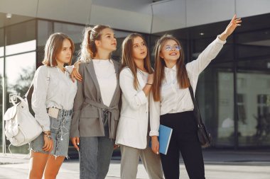 Elinde kitaplarla çimlerin üzerinde yatan üç öğrenci.