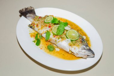 Beyaz tabakta limon soslu balık buğulama