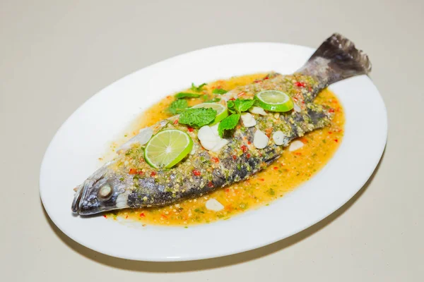 Риба на пару в лимонному соусі на білій тарілці — стокове фото