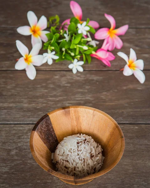 Cooked rice in wood bowl and flower on table — Stock Photo, Image