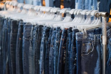 Row of Jeans and trousers on hangers for sale. clipart
