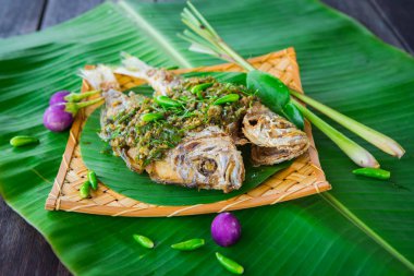 Derin kızarmış balık muz yaprak üzerinde kırmızı sos ile