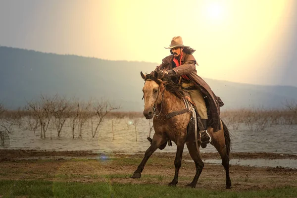 Muž v kovbojském kostýmu na koni v koutě proti — Stock fotografie