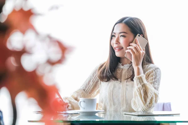 Asijská podnikatelka sedí, pracuje a mluví po telefonu — Stock fotografie