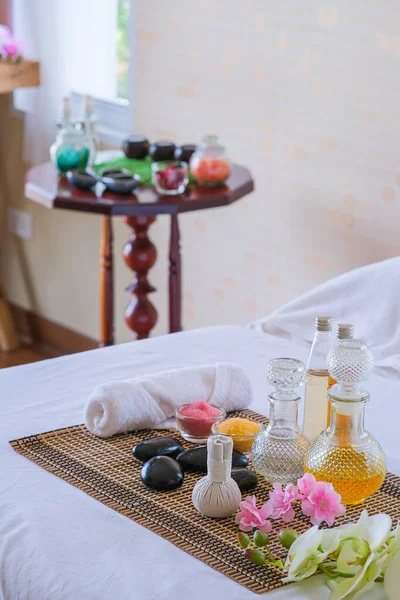 トリートメントセットとアロママッサージオイルをベッドマッサージで タイの香りの治療とベッドの上の花とマッサージの設定 リラックスして健康的なケア — ストック写真