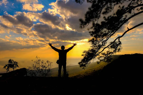 山の中で日没を探して崖の上に男のシルエット — ストック写真