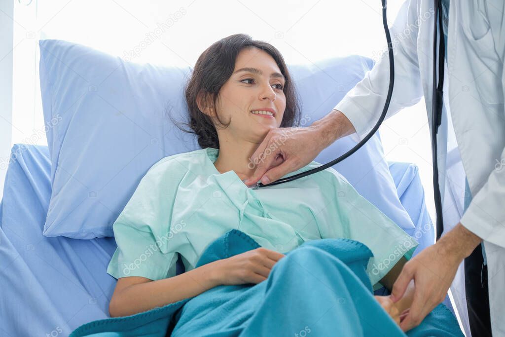 The doctor listened to the female patient's heartbeat on the bed in the hospital room