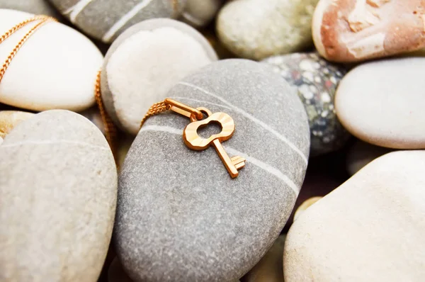 Zlatý klíč na moře oblázky — Stock fotografie